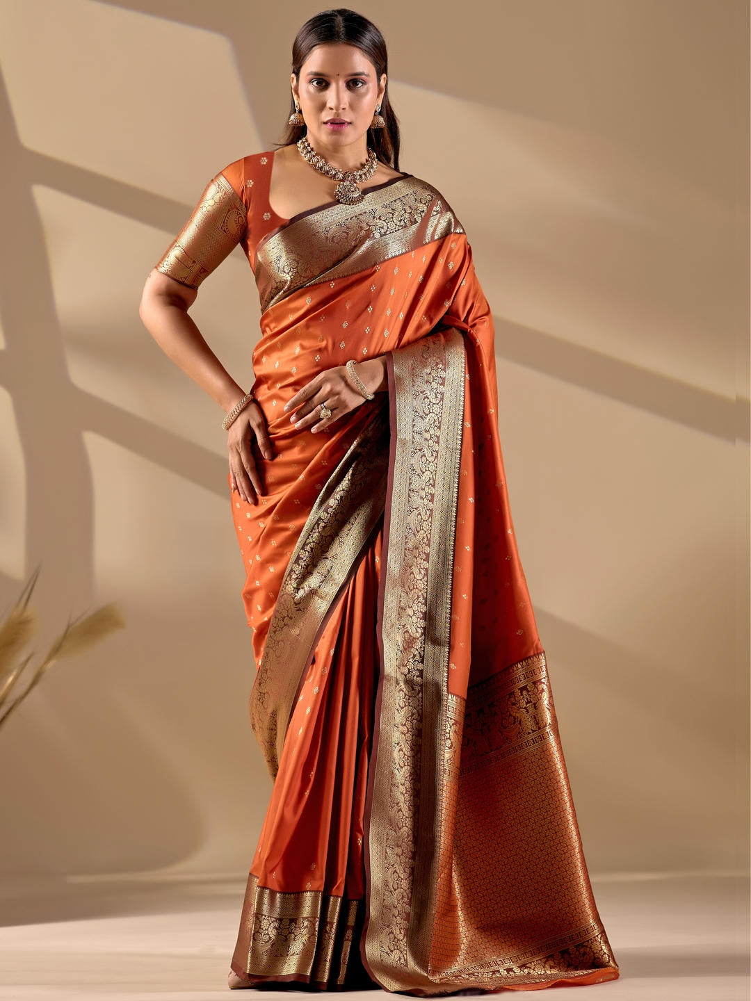Beautiful woman styled in an orange woven design silk saree featuring a heavy zari border and solid blouse by Samantha.