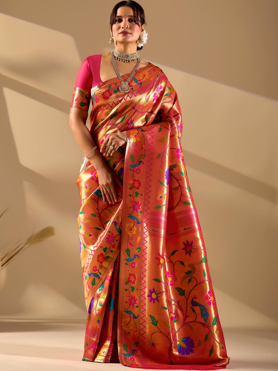 Beautiful woman styled in a red gold woven design silk saree featuring a heavy zari border and solid blouse by Samantha.