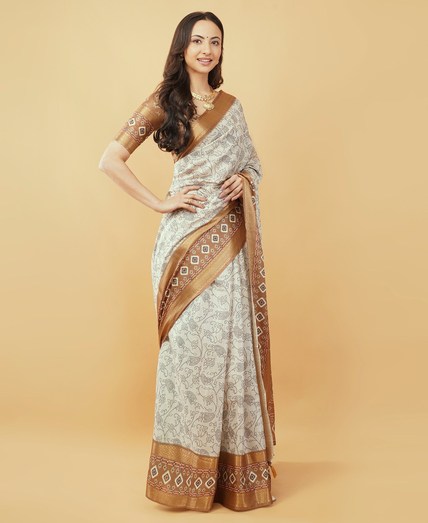 Cream floral saree with maroon geometric zari border and tassel pallu