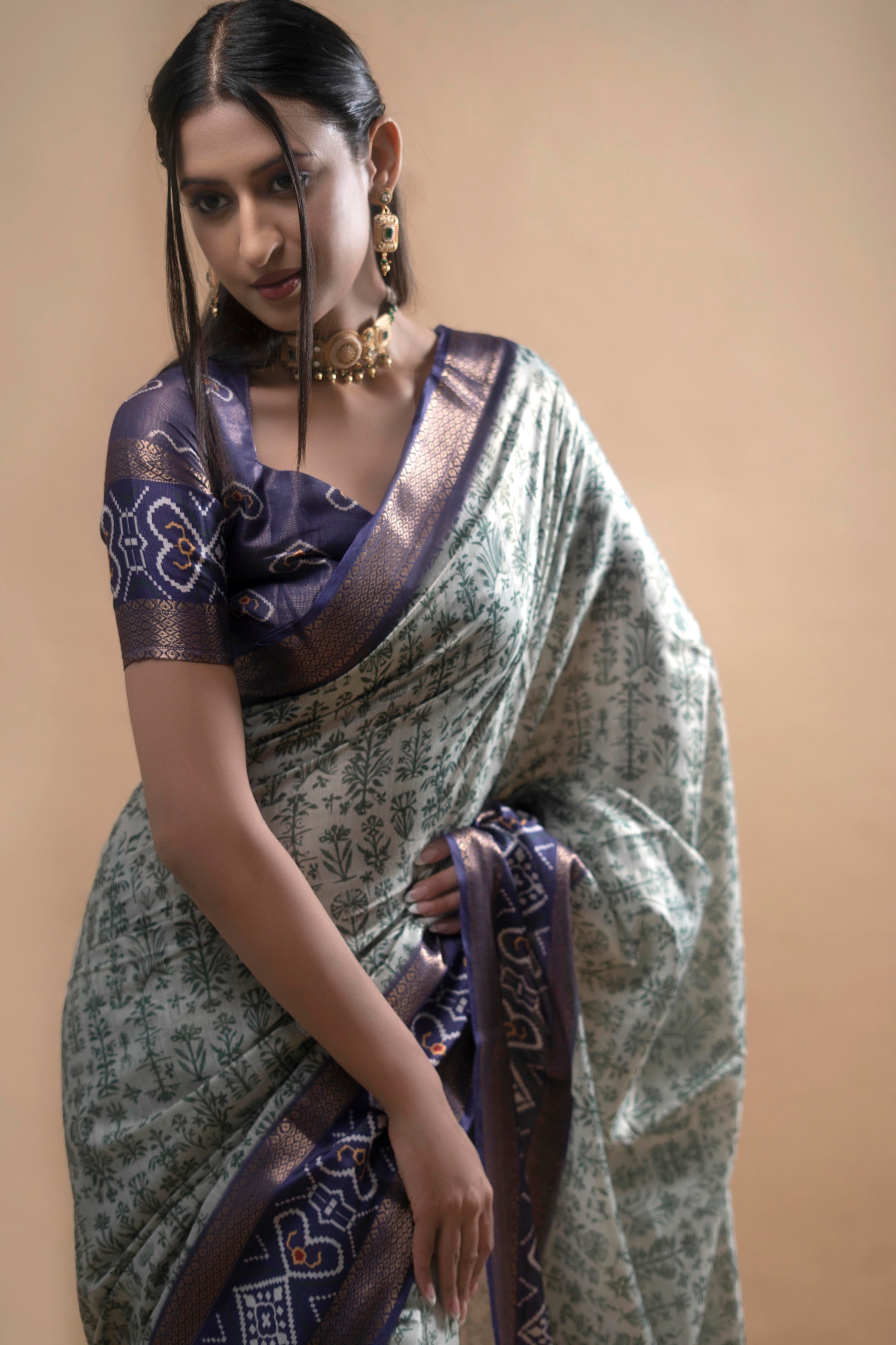 Off-white and green floral saree with patola print pallu and ruched indigo blouse
