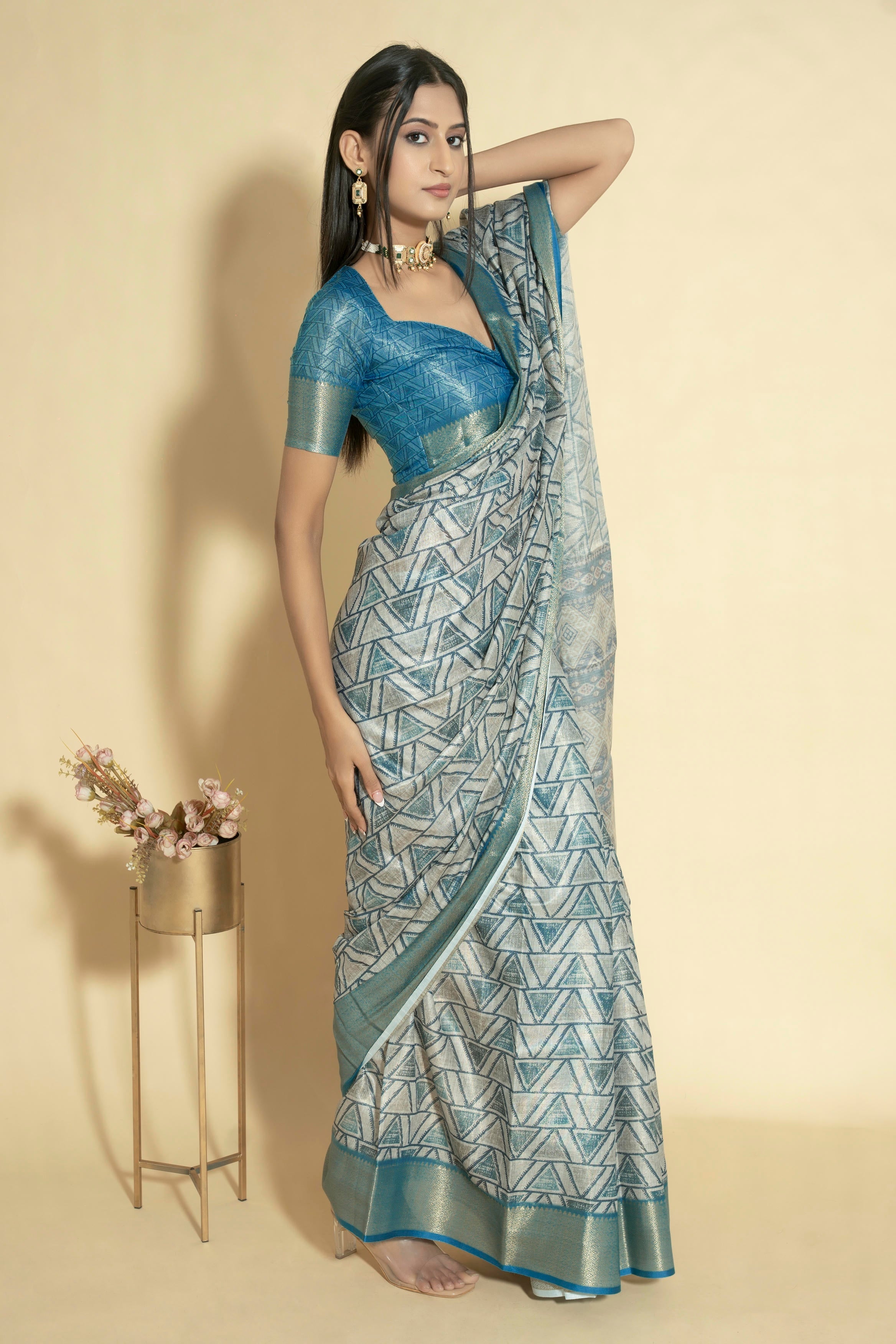 Silver grey geometric triangle print saree with muted gold zari border and teal blue ruched blouse