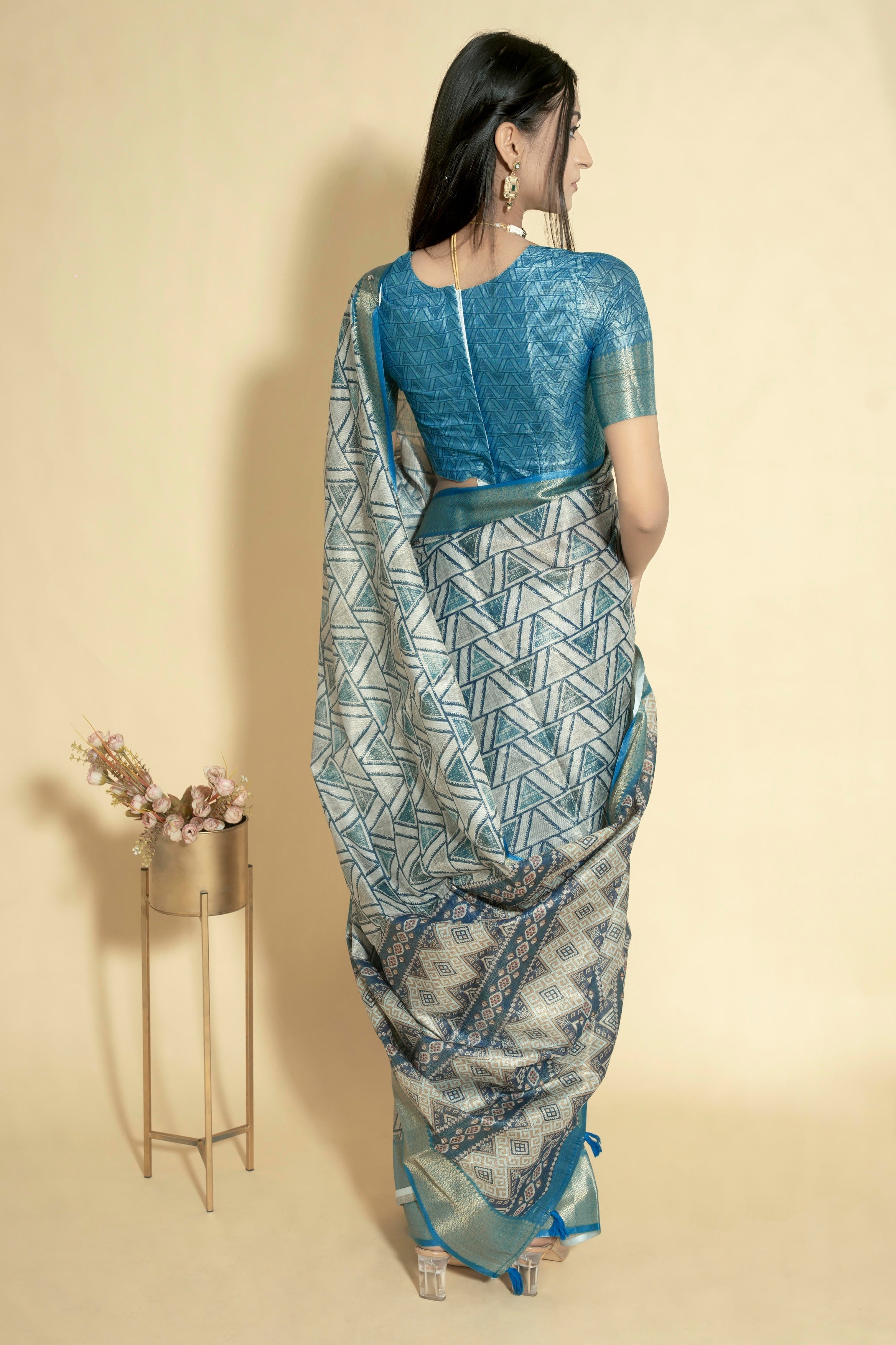 Silver grey geometric triangle print saree with muted gold zari border and teal blue ruched blouse