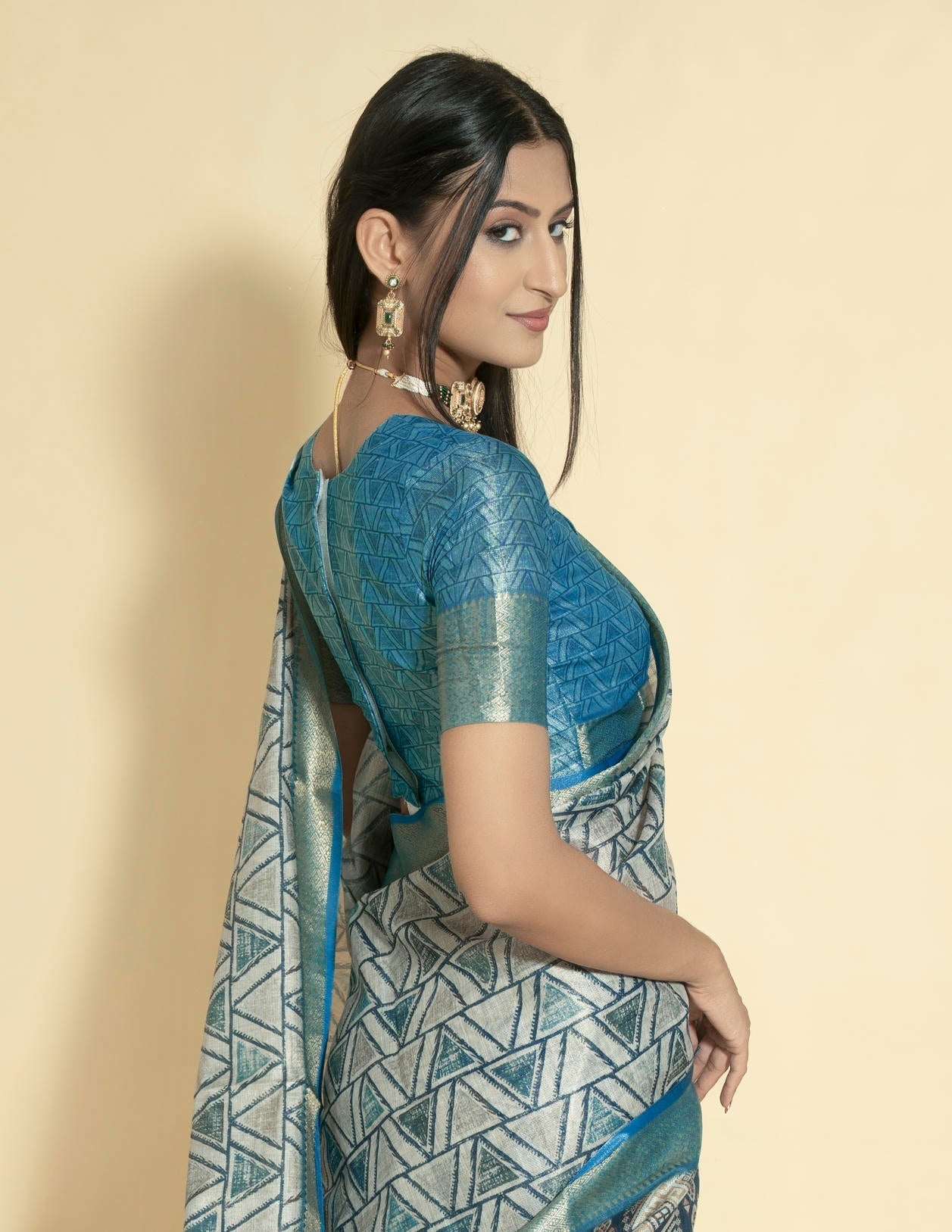 Silver grey geometric triangle print saree with muted gold zari border and teal blue ruched blouse
