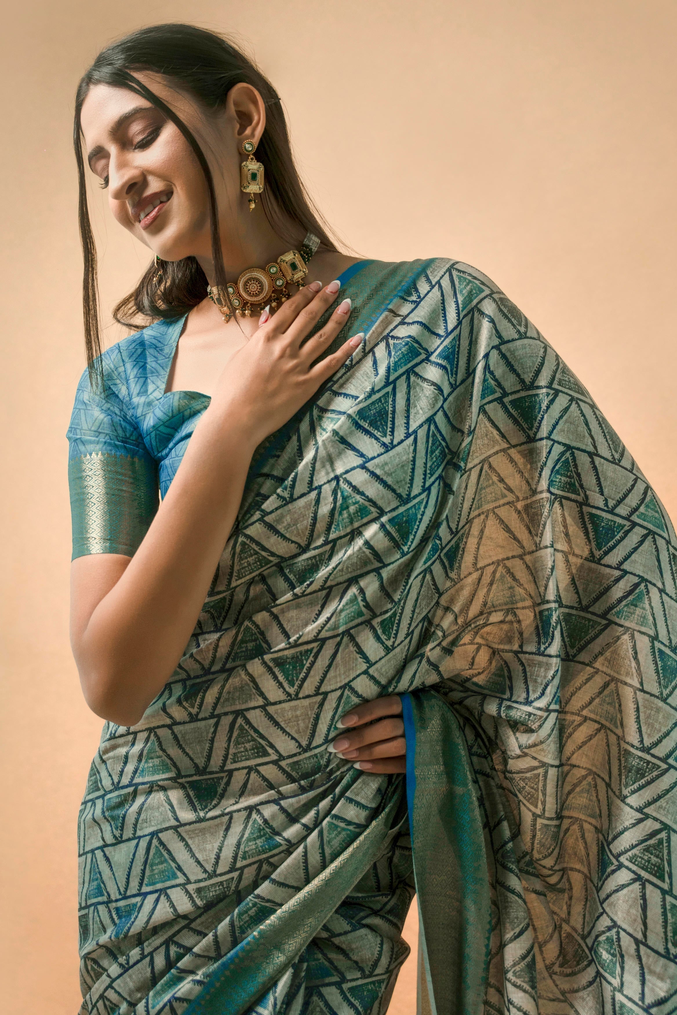 Silver grey geometric triangle print saree with muted gold zari border and teal blue ruched blouse