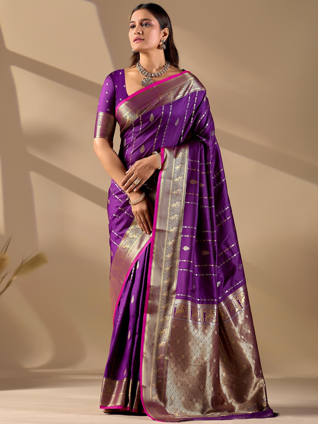 Beautiful woman styled in a royal purple woven design silk saree featuring a heavy zari border and solid blouse by Samantha.