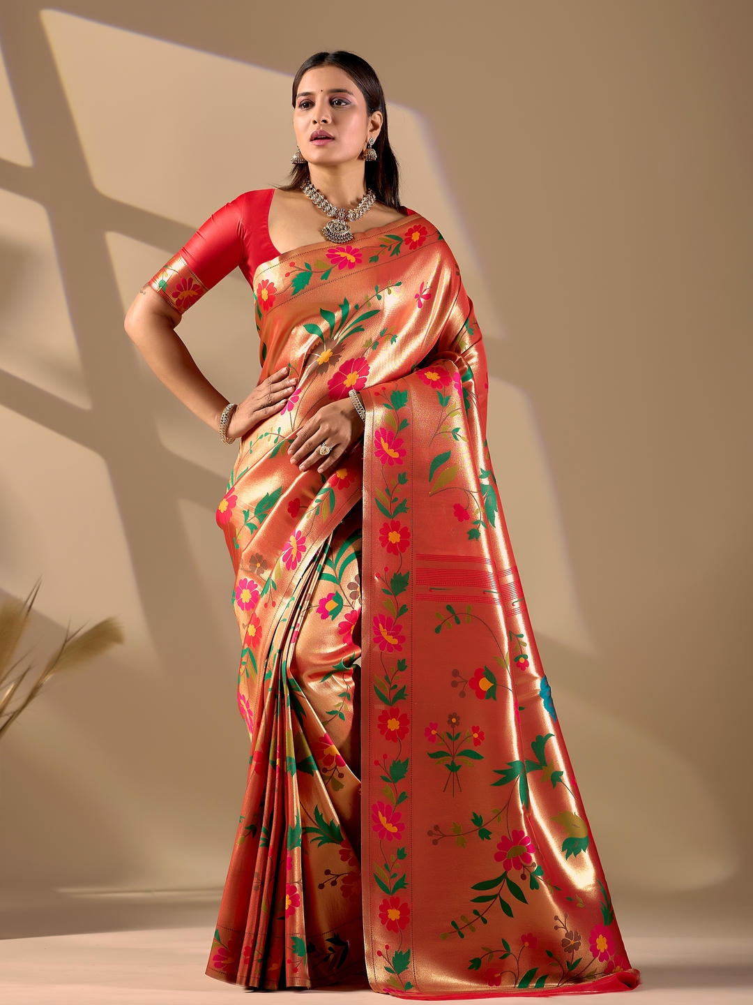 Beautiful woman styled in a red gold woven design silk saree featuring a heavy zari border and solid blouse by Samantha.