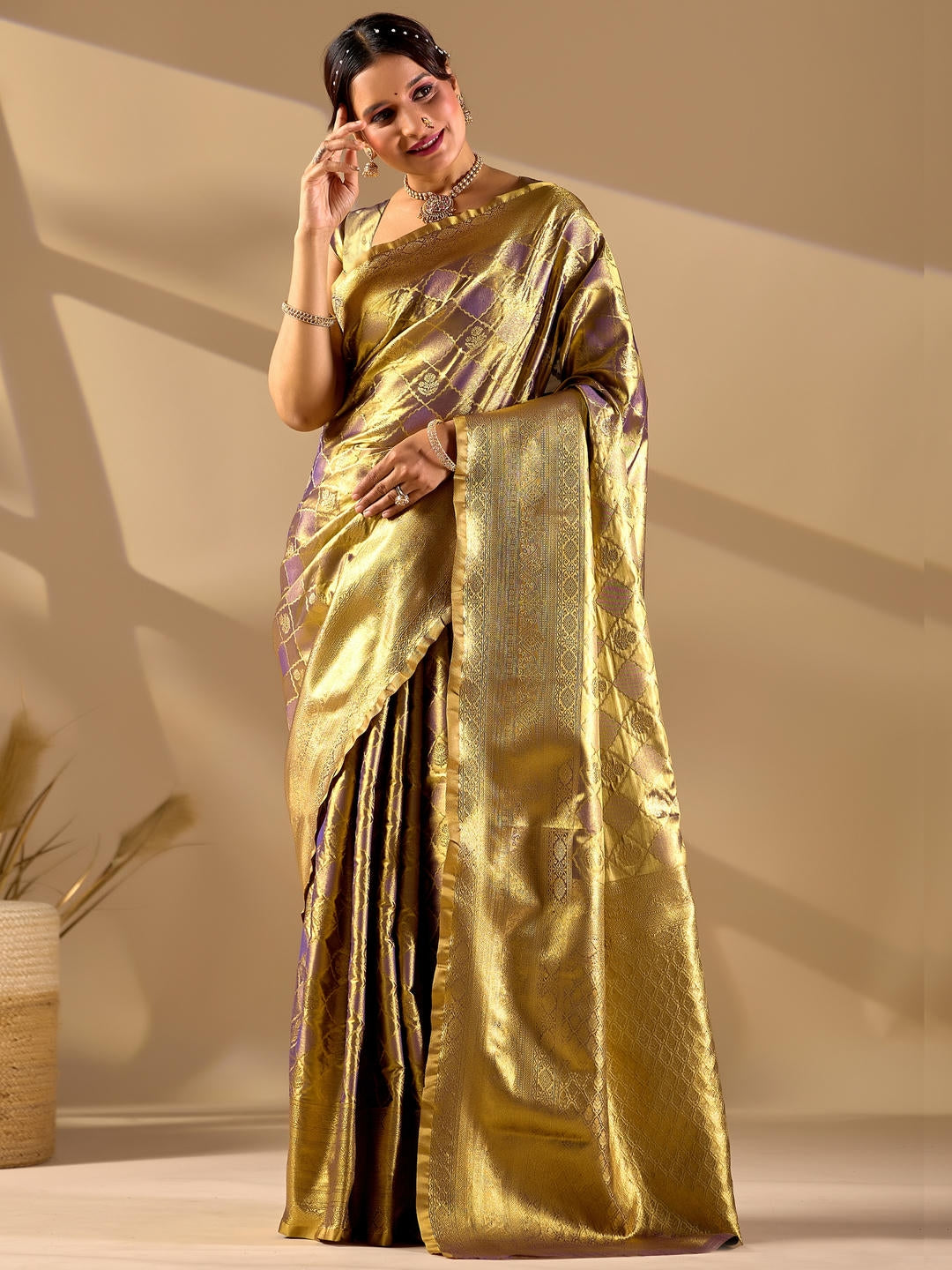 Beautiful woman styled in a rusty gold woven design silk saree featuring a heavy zari border and solid blouse by Samantha.