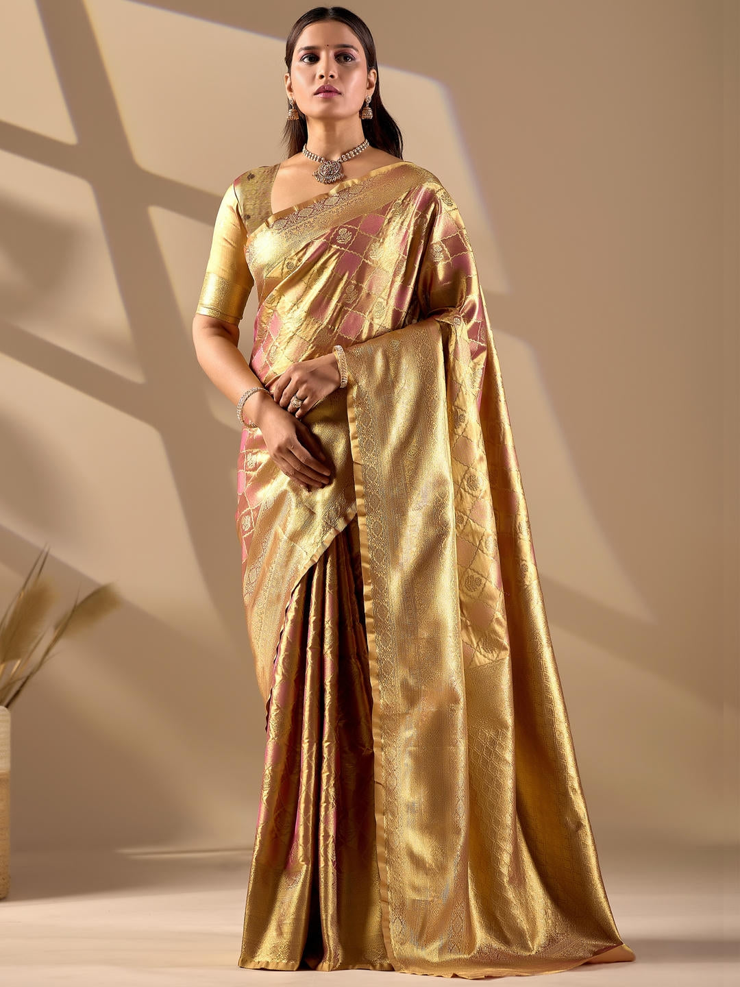 Beautiful woman styled in a beige gold woven design silk saree featuring a heavy zari border and solid blouse by Samantha.