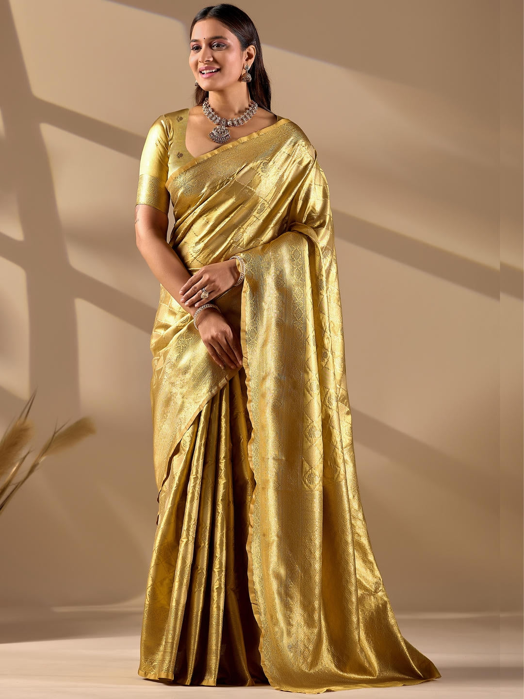 Beautiful woman styled in a metallic gold woven design silk saree featuring a heavy zari border and solid blouse by Samantha.