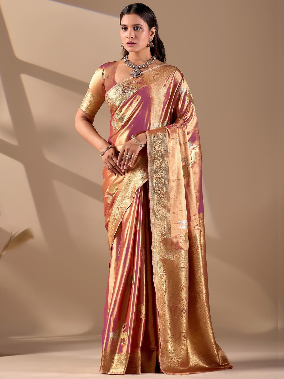 Beautiful woman styled in a peach gold woven design silk saree featuring a heavy zari border and solid blouse by Samantha.