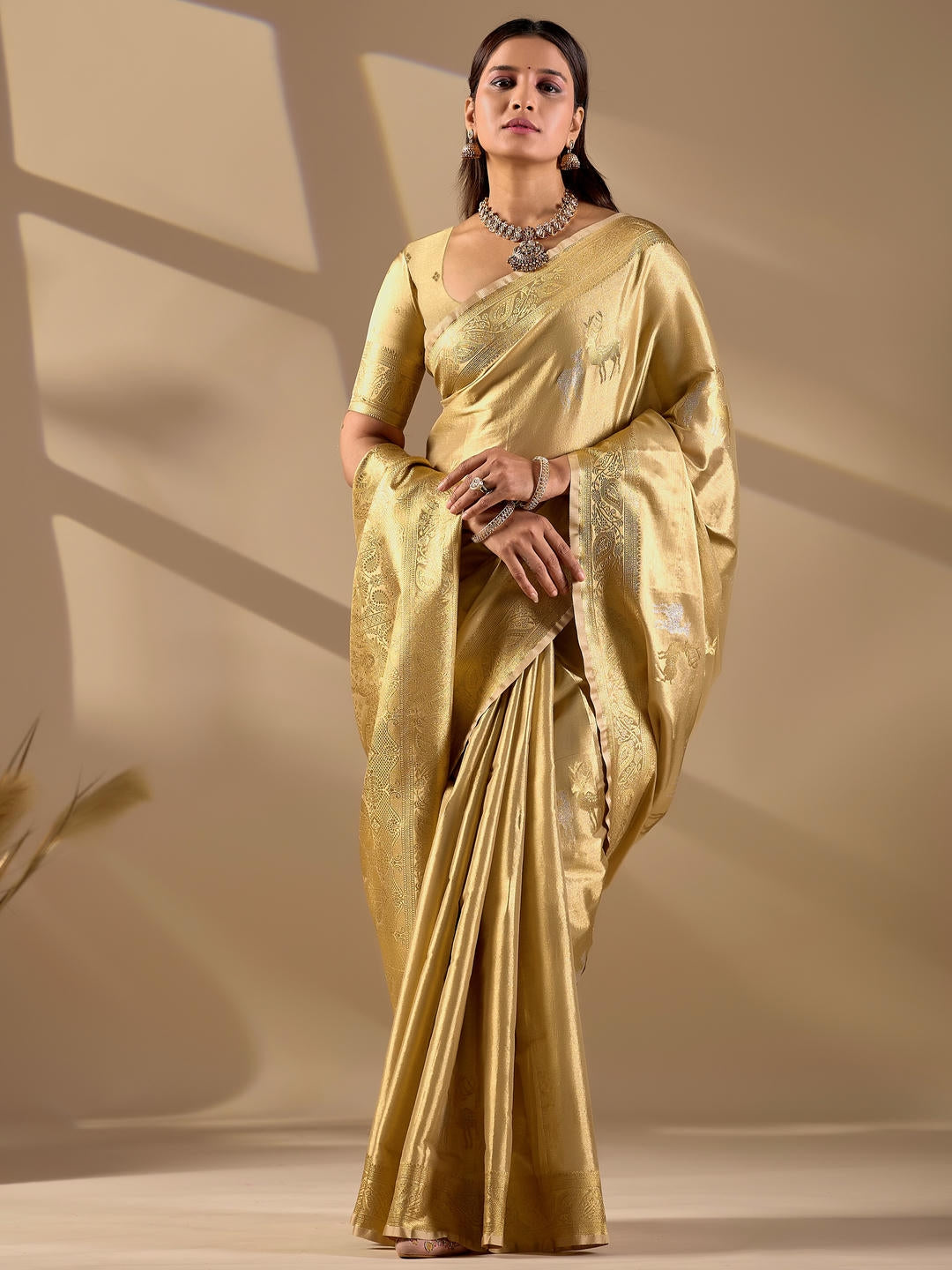 Beautiful woman styled in a beige woven design silk saree featuring a heavy zari border and solid blouse by Samantha.