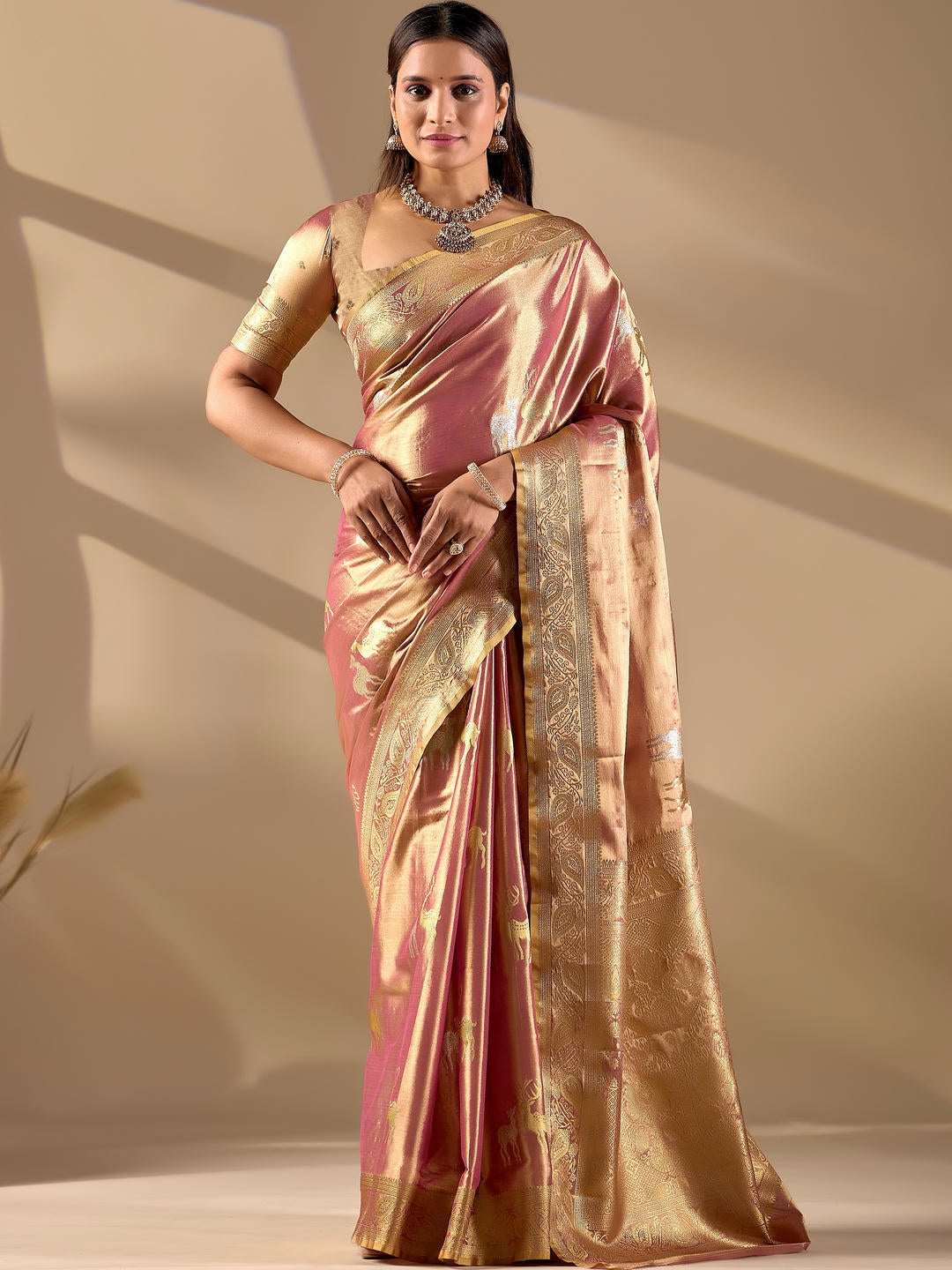 Beautiful woman styled in a peach woven design silk saree featuring a heavy zari border and solid blouse by Samantha.