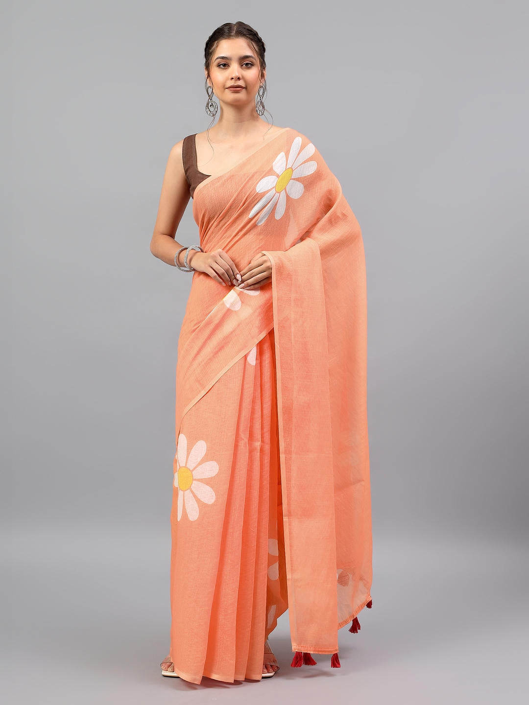 Beautiful woman styled in a breezy peach art linen saree with bold white daisy prints and red tassels by Samantha.