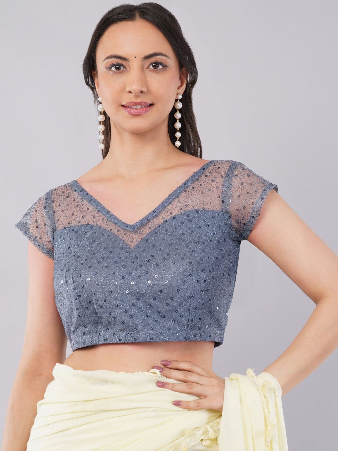 Woman wearing silver grey sequin blouse with sheer illusion neckline