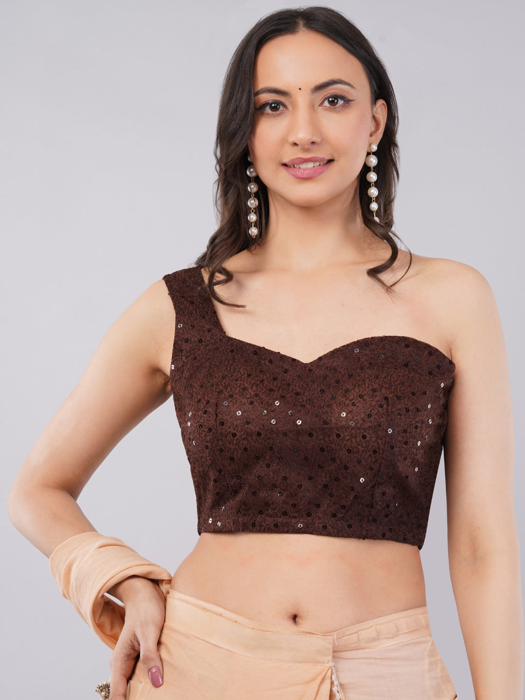 Woman wearing claret wine sequin one-shoulder blouse with peach saree