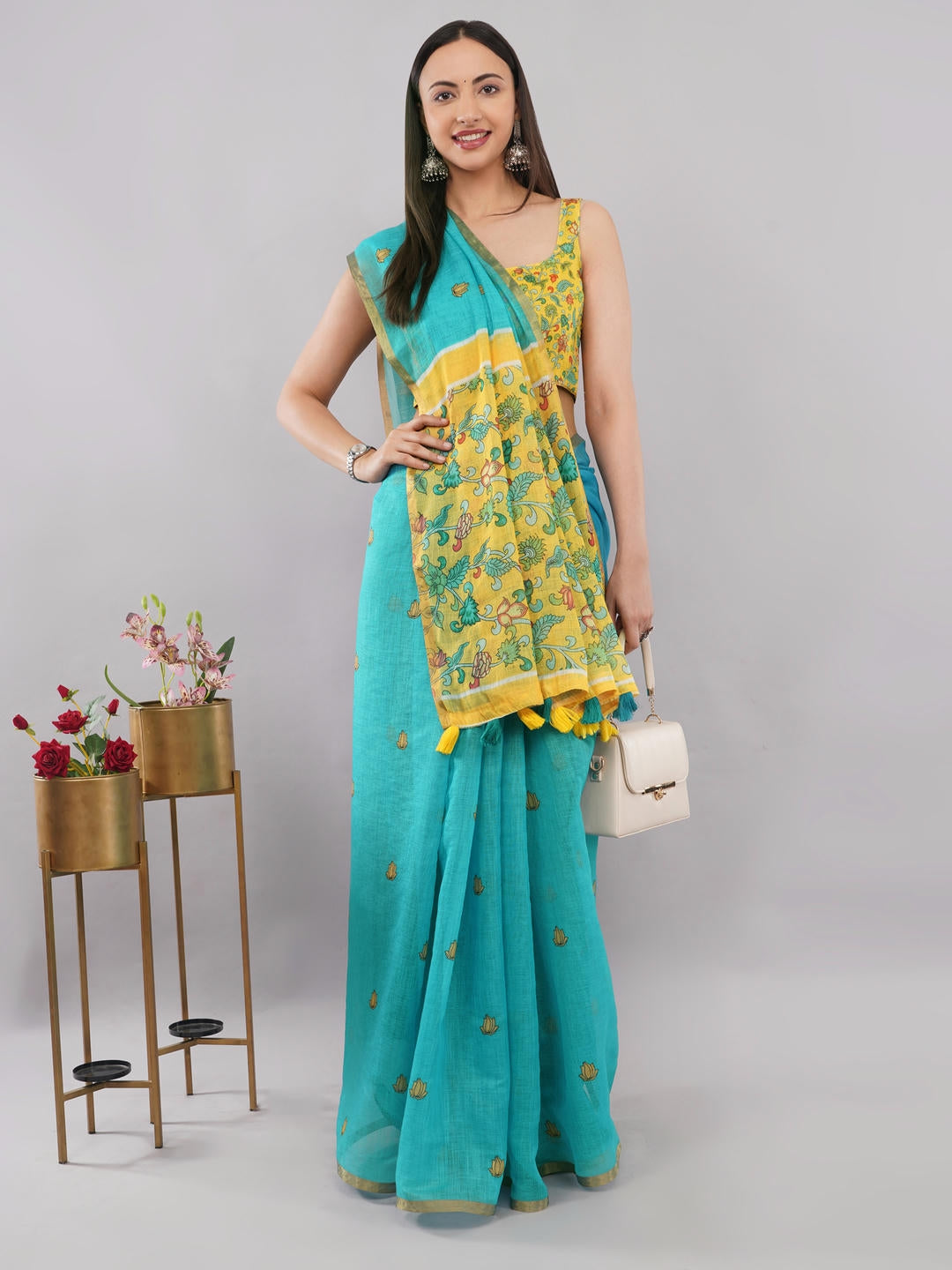 Beautiful woman styled in a classic off white linen saree featuring bold blue floral prints, a geometric border, and a matching unstitched blouse by Samantha.