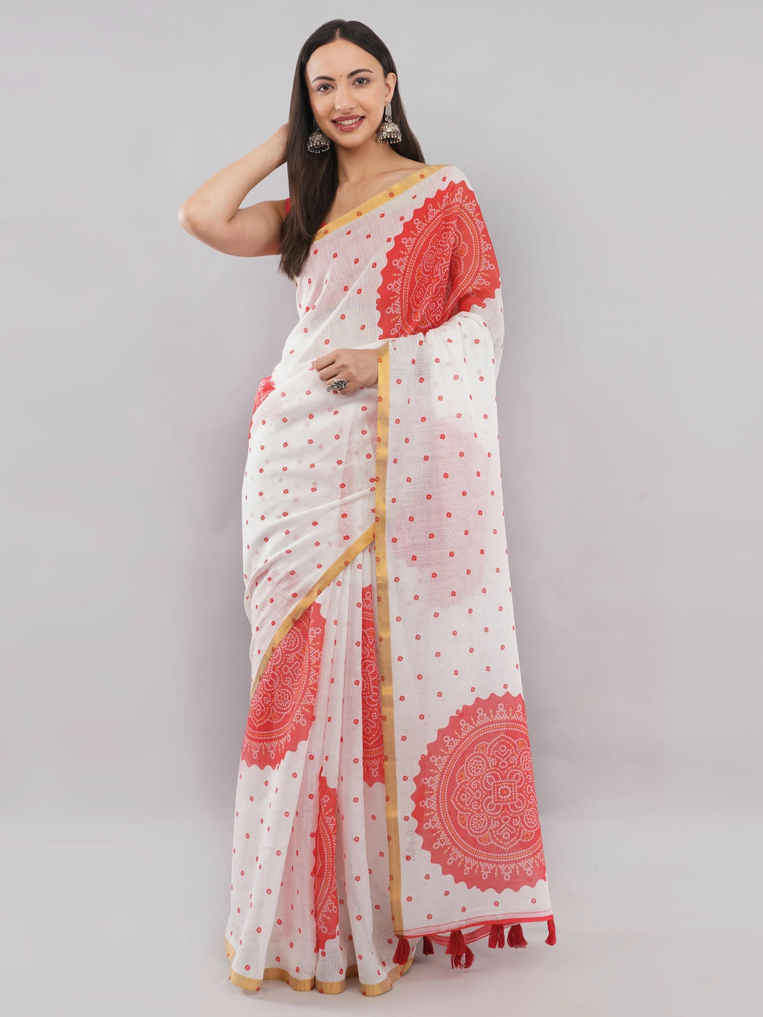 Beautiful woman styled in a classic white linen saree featuring traditional red bandhani and mandala prints, a subtle gold border, and a matching unstitched red blouse by Samantha.